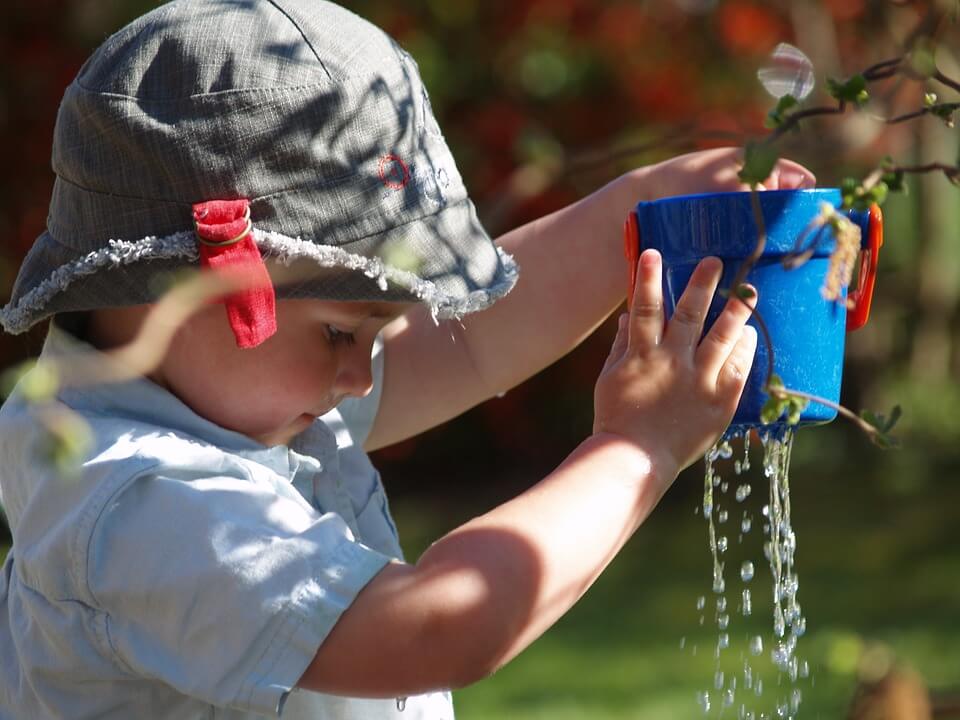 ילד מחזיק דלי עם חור בקרקעית ממנו נוזלים מים. להתאושש מהוצאות החג - להימנע מהפיתוי של הלוואה